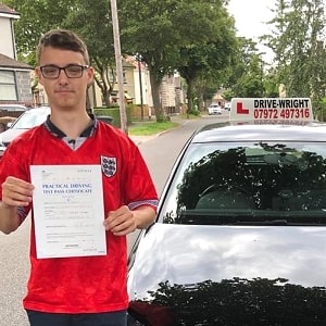 Joshua stood next to the driving school car with his driving test certificat.e