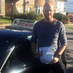Peter stood next to the driving school car with his driving test certificate