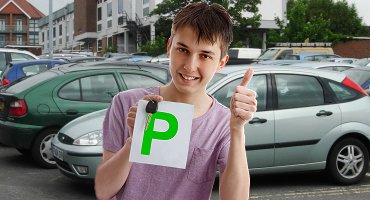 Young male student holding green driving pass plate